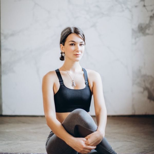 Person sitting in a calm, meditative yoga pose against a neutral background.